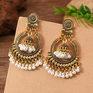 Detail of vintage ethnic drop earrings with antique gold finish and white bead tassels