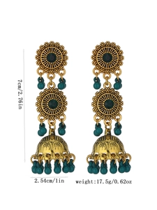 Dettaglio di orecchini jhumka dorati con pietre blu e nappine di perline vintage