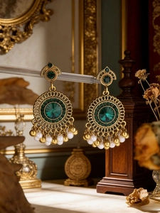Detail of vintage gold earrings featuring green gemstones and white pearl tassels