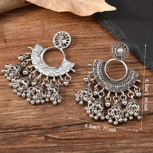 Bohemian retro silver drop earrings with bells on a rustic wood and stone background