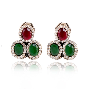 Detailed macro view of vintage gold stud earrings with oval red and green gemstones