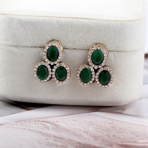 Macro detail of vintage three-stone green gemstone earrings with white rhinestone halo