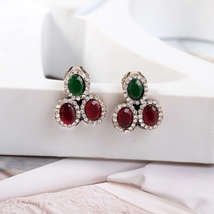 Macro shot of vintage gold earrings with red and green gemstones and crystal pavé