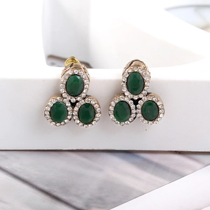 Macro shot of vintage cluster earrings with oval green stones and rhinestone halo