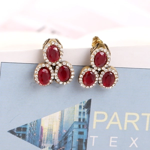 Close-up of vintage bronze earrings with red oval gemstones and white diamond accents