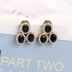 Detailed view of vintage black gemstone earrings with gold base and white crystal borders