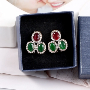 Macro view of vintage style earrings with red and green gems in a blue jewelry gift box