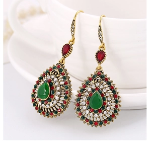 Detail of vintage bohemian drop earrings with colorful crystals hanging on a white cup