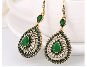 Detailed macro of vintage bohemian waterdrop earrings with green crystals and gold finish