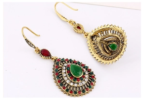 Macro shot of vintage bohemian teardrop earrings with green crystal and colorful rhinestones