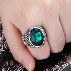 Detailed close-up of a men's vintage alloy ring with woven texture and a large green gemstone