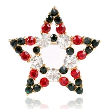 Vue détaillée d'une broche étoile dorée avec strass rouges et noirs pour les fêtes de Noël