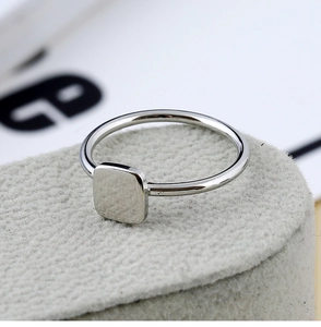 Vue macro d'une bague carrée minimaliste en métal argenté avec une surface polie