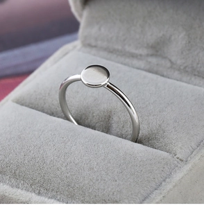 Gros plan sur une bague ronde argentée présentée dans un coffret à bijoux en velours gris