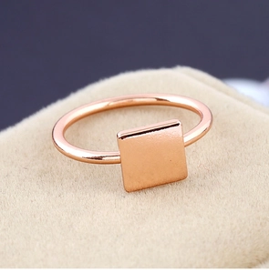 Gros plan d'une bague carrée minimaliste en or rose sur un écrin à bijoux en velours