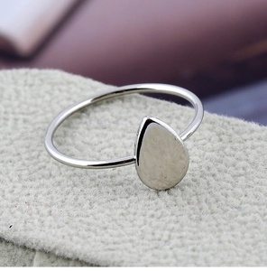 Vue macro d'une bague argentée polie avec un plateau en forme de poire sur tissu doux