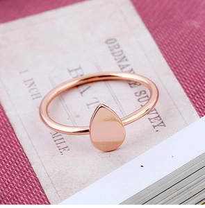 Détail d'une bague goutte en or rose sur fond vintage avec finition polie