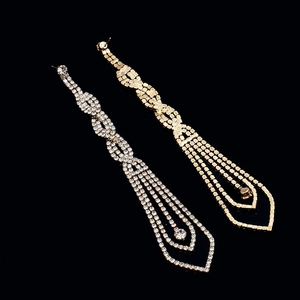 Close-up of long tassel rhinestone earrings in gold and silver with woven link detail
