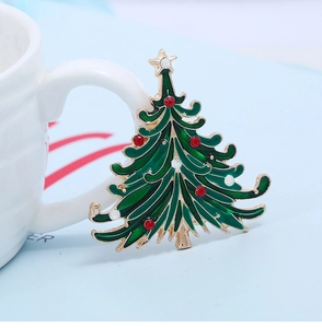 Close-up of green enamel Christmas tree brooch with sparkling red and white rhinestones