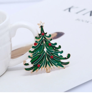 Detailed view of enamel Christmas tree brooch with rhinestones next to white mug