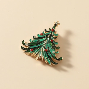 Christmas tree brooch pin in green enamel with red rhinestones on beige background