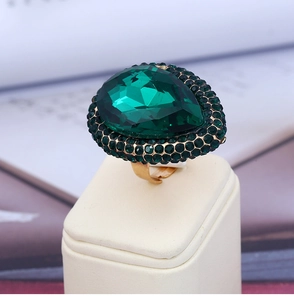 Macro shot of green pear-cut gemstone ring with emerald accents on golden adjustable band