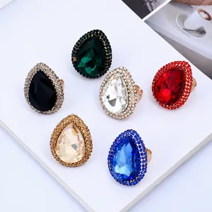 Macro shot of colorful pear-cut crystal rings with pavé halos in six vibrant shades