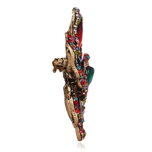 Vintage gold hollow flower brooch with emerald and ruby crystals on white background