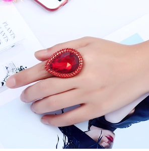 Macro view of luxury gold ring with large red pear-cut ruby and surrounding halo setting