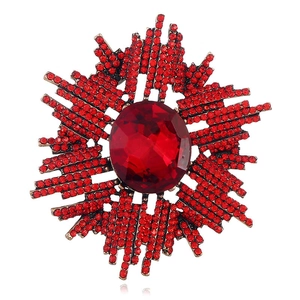 Vue détaillée de la broche soleil avec gemme rouge ovale et strass étincelants
