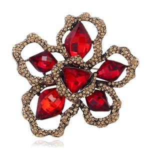 Macro detail of red marquise crystal flower brooch with gold plating and rhinestones