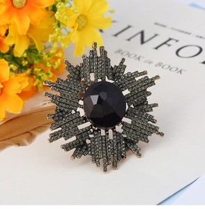 Détail d'une broche étoile vintage avec gemme noire et strass vert olive sur métal