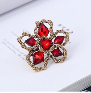 Detailed view of red gemstone flower brooch with gold petals on a white magazine background