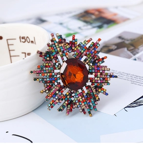 Détail d'une broche soleil vintage avec pierre ambre et strass colorés sur métal antique
