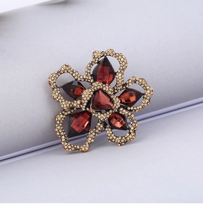 Detail of vintage flower brooch with red-brown gemstones and golden rhinestones