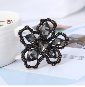 Detailed view of flower brooch with grey crystals and black rhinestones on gold base