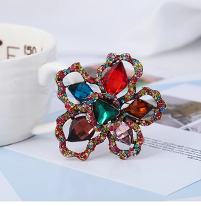 Macro shot of colorful crystal flower brooch with a green center stone and vintage metal frame