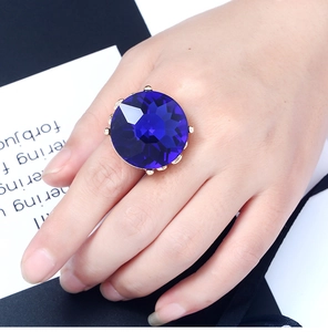 Detail of large round blue gemstone ring with gold claw setting on hand
