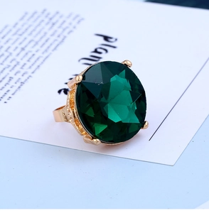 Close-up of a large round faceted green gemstone ring with vintage gold relief texture