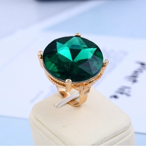 Macro shot of a large faceted emerald green gemstone set in a gold textured metal ring