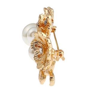 Détail de la broche fleur dorée avec perles et strass brillants en gros plan