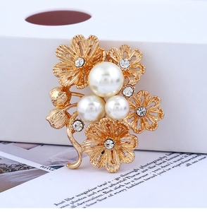 Détails d'une broche florale dorée ornée de perles blanches et de strass étincelants