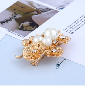 Gros plan détaillé d'une broche fleurie dorée ornée de perles et de strass brillants