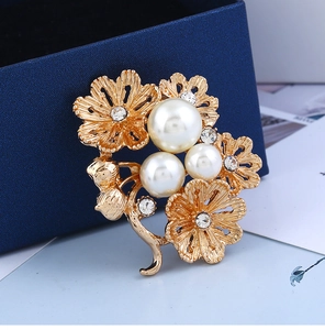 Détails de la broche fleur dorée ornée de perles blanches et de strass brillants