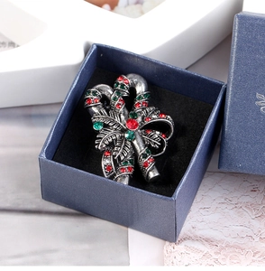 Detailed view of vintage candy cane brooch with red and green rhinestones in a gift box