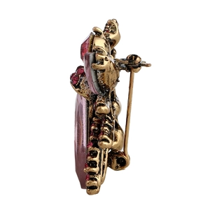Vintage gold alloy brooch with large pink crystal and deep red accents on white background