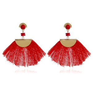 Detail shot of bohemian fan-shaped earrings with dense red silk tassels and gold accents