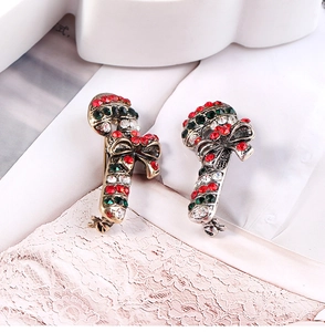 Detail of candy cane brooches with red and green rhinestones and bows on fabric