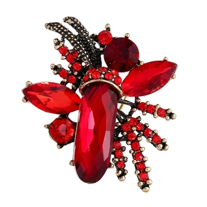Macro detail of retro insect brooch with red gemstones and crystals on bronze alloy base