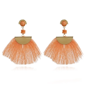 Macro shot of bohemian fan-shaped earrings with coral orange tassels and golden studs